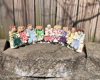 Handmade pottery ceramic menorah of small children holding hands seated on a bench, nine candle menorah. Signed Heny 1992
