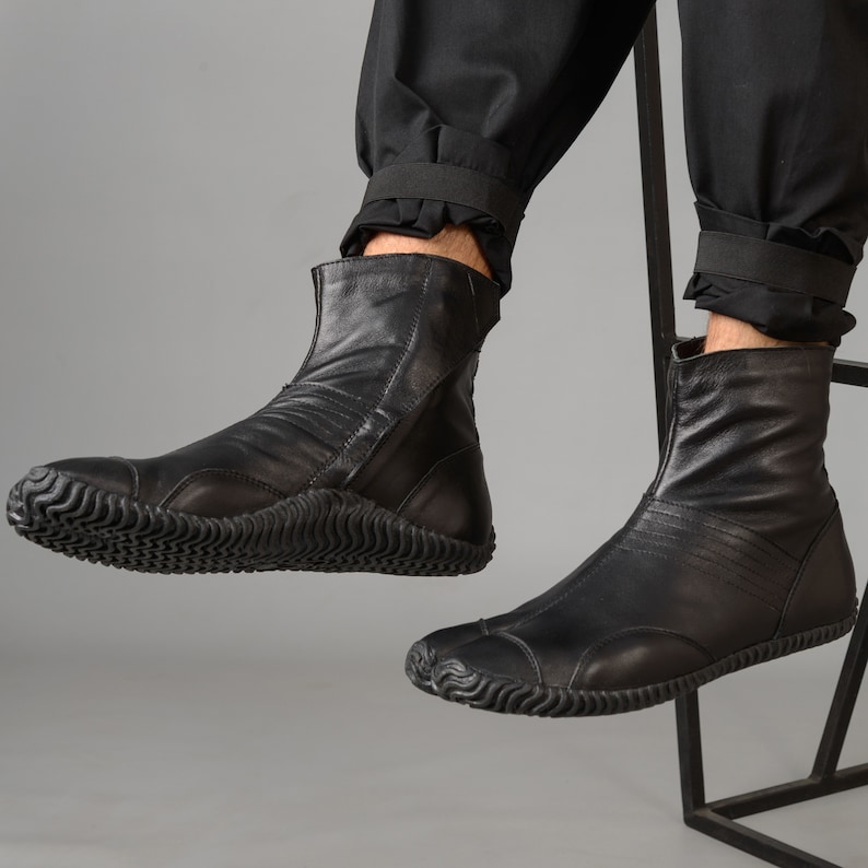 May include: Black leather ankle boots with a zipper on the side and a thick rubber sole. The boots have a pointed toe and a slightly raised heel.