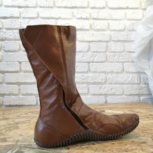 Puede incluir: Botas de cuero marr&oacute;n de ca&ntilde;a alta con cremallera lateral y suela texturizada.