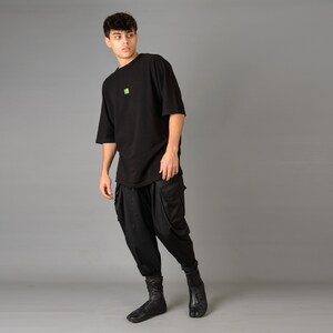 May include: A black oversized t-shirt with a small colorful logo on the chest, paired with black cargo pants and black ankle boots.