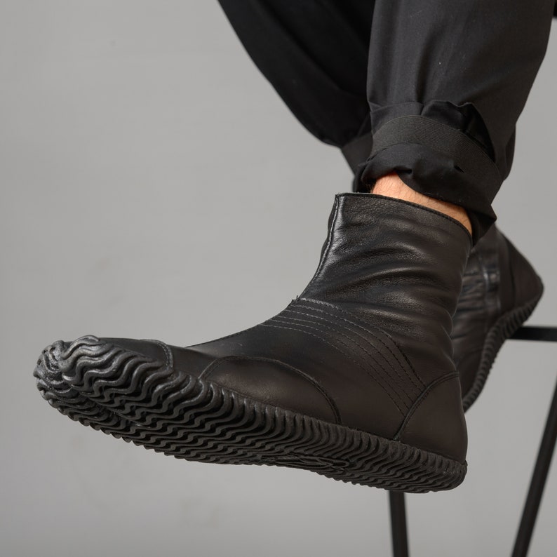 May include: Black leather ankle boots with a textured rubber sole. The boots have a zipper on the side and a pointed toe.