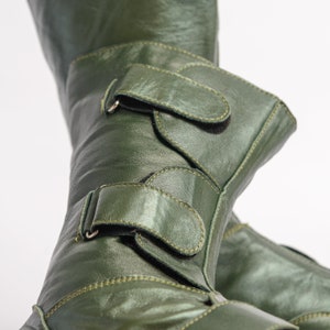 Puede incluir: Un par de botas de cuero verde con dos correas ajustables y hebillas. Las botas tienen un acabado brillante y est&aacute;n hechas de cuero de alta calidad.