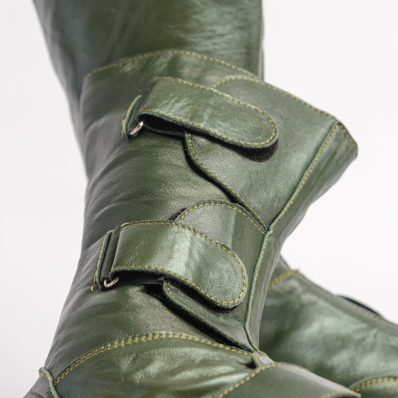 Puede incluir: Un par de botas de cuero verde con dos correas ajustables y hebillas. Las botas tienen un acabado brillante y est&aacute;n hechas de cuero de alta calidad.