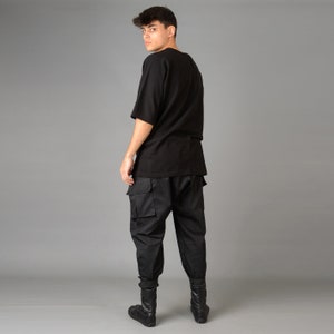 May include: A black short-sleeved t-shirt with a relaxed fit and black cargo pants. The person is wearing black ankle boots.