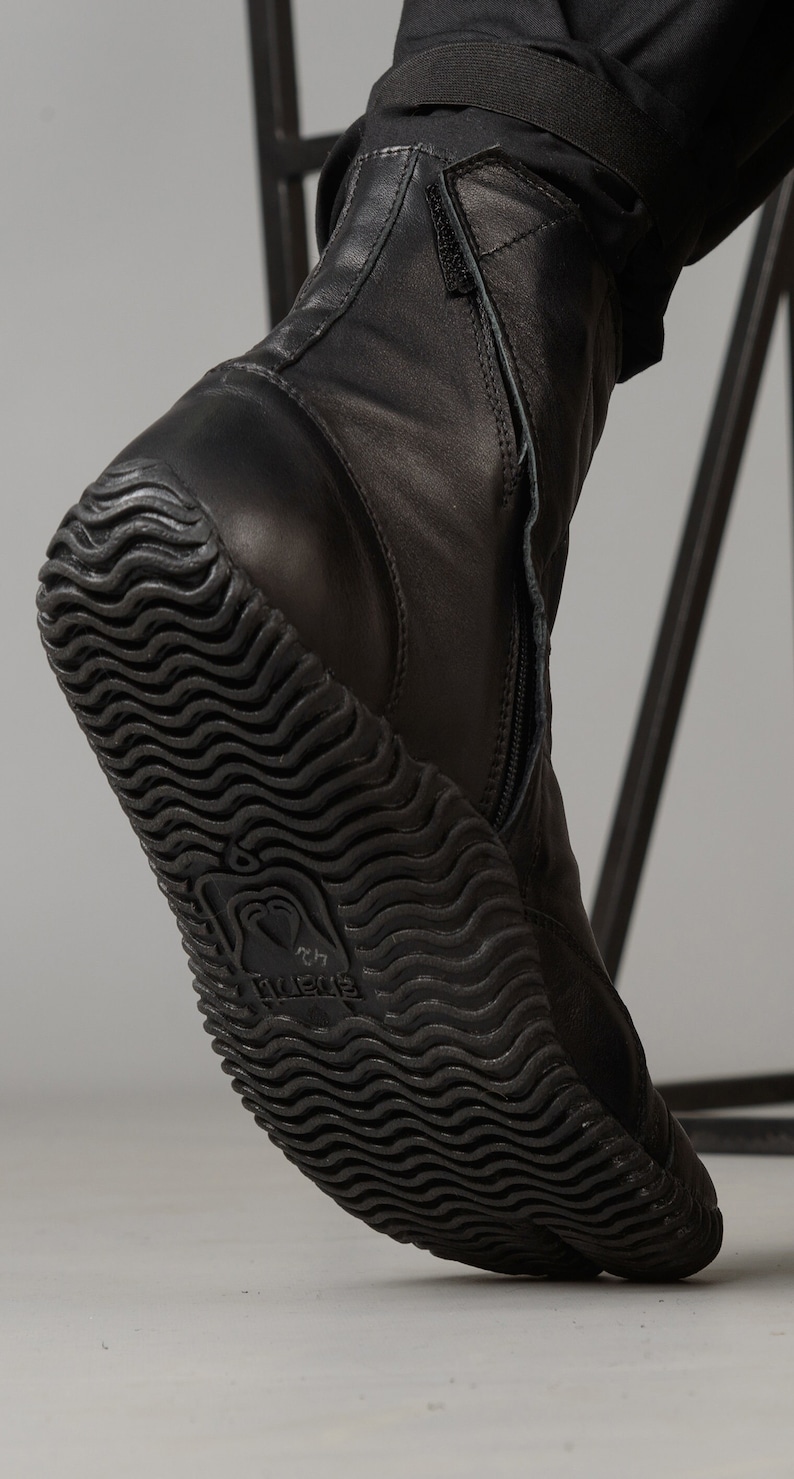 May include: Black leather ankle boots with a zipper up the back and a textured rubber sole. The sole has the word "Vibram" printed on it.
