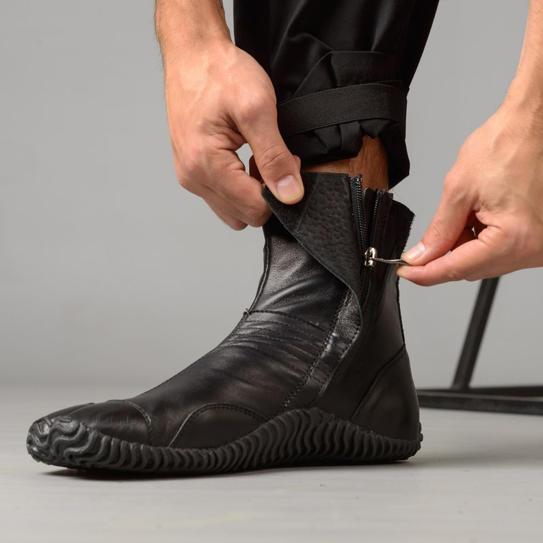 May include: Black leather ankle boots with a zipper on the side and a textured rubber sole.