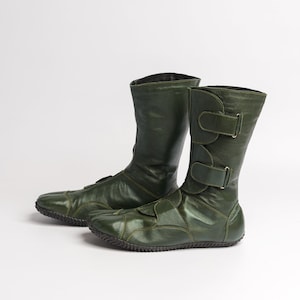 Puede incluir: Un par de botas de cuero verde oscuro con un dise&ntilde;o &uacute;nico. Las botas tienen una punta puntiaguda y un cierre de hebilla en el lateral.