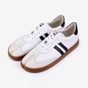 Könnte beinhalten: Weiße Sneaker mit geteiltem Zehendesign, schwarzen Streifen und brauner Sohle. Die Schuhe haben weiße Schnürsenkel und schwarze Akzente an der Ferse. Ein moderner Twist auf einen klassischen Stil.