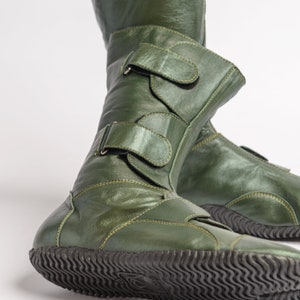 Puede incluir: Un par de botas de cuero verde con m&uacute;ltiples correas y hebillas. Las botas tienen una suela de goma texturizada.