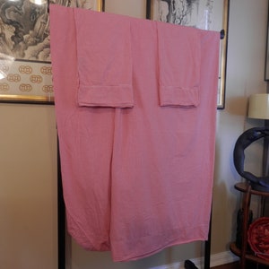Op de afbeelding: Twee kussenslopen met roze en witte ruitjes, hangend aan een rek.