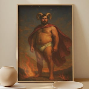 Puede incluir: Una impresión enmarcada de un hombre con cuernos de carnero, con una capa roja y calzoncillos blancos, de pie frente a un fuego. La obra de arte se exhibe sobre una mesa de madera clara con un jarrón beige, libros y un cuenco.