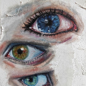 Puede incluir: Tres ojos pintados en una pared blanca texturizada. El ojo superior es azul con un iris azul oscuro y un p&aacute;rpado rojo. El ojo del medio es verde con un iris marr&oacute;n y un p&aacute;rpado azul. El ojo inferior es azul con un iris verde y un p&aacute;rpado azul.