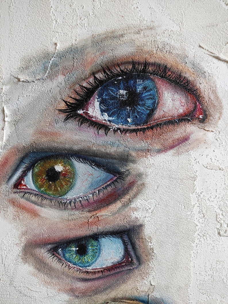 Puede incluir: Tres ojos pintados en una pared blanca texturizada. El ojo superior es azul con un iris azul oscuro y un p&aacute;rpado rojo. El ojo del medio es verde con un iris marr&oacute;n y un p&aacute;rpado azul. El ojo inferior es azul con un iris verde y un p&aacute;rpado azul.