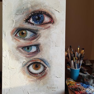 Puede incluir: Una pintura sobre lienzo blanco con cuatro ojos pintados en ella. Los ojos son de diferentes colores y tienen diferentes expresiones. La pintura est&aacute; firmada "Kushnir I. 2022" en la esquina inferior derecha.
