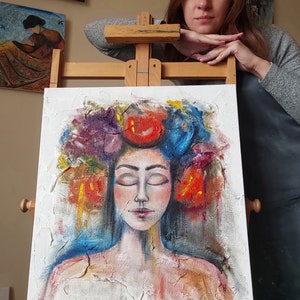 Pu&ograve; includere: Un dipinto di una donna con gli occhi chiusi, che indossa una corona di fiori colorati. Il dipinto &egrave; su una tela bianca con una superficie strutturata. Il viso della donna &egrave; dipinto in uno stile realistico, con tratti delicati e un'espressione serena. La corona &egrave; composta da fiori rossi, blu e viola brillanti. Lo sfondo del dipinto &egrave; di colore azzurro chiaro.