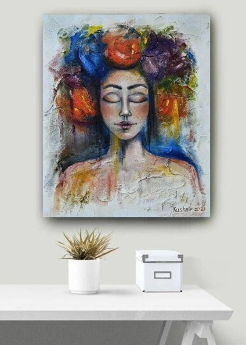 Pu&ograve; includere: Un dipinto astratto colorato di una donna con gli occhi chiusi. Indossa una corona di fiori in tonalit&agrave; di blu, viola, rosso e giallo. Lo sfondo &egrave; grigio chiaro con accenni di blu e giallo.