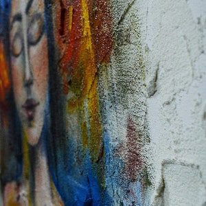 Pu&ograve; includere: Dipinto astratto di un viso di donna con vernice blu, gialla, rossa e bianca. Il viso della donna &egrave; parzialmente oscurato dalla vernice.