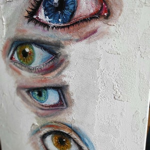 Puede incluir: Una pintura de cuatro ojos, cada uno con un iris de color diferente. Los ojos est&aacute;n pintados en un estilo realista, con detalles como pesta&ntilde;as y vasos sangu&iacute;neos. El fondo es una superficie blanca texturizada.