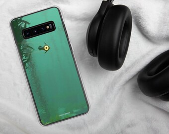 May include: A green phone case with a clear back and a yellow and black graphic of a creature from the video game Subnautica. The case is lying on a white surface next to a pair of black headphones.