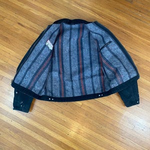 May include: Black denim jacket with a striped flannel lining. The lining has red and black stripes.
