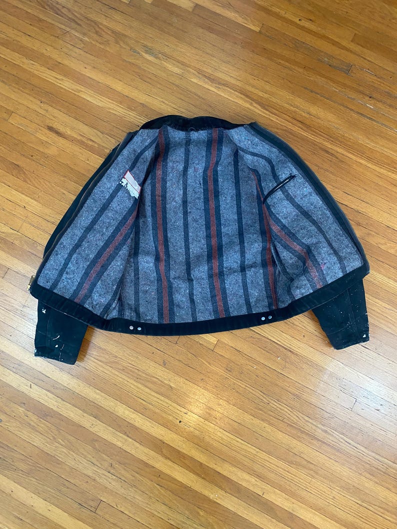 May include: Black denim jacket with a striped flannel lining. The lining has red and black stripes.