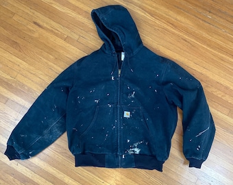 Chaqueta bomber vintage Carhartt con capucha negra desgastada y forro de malla. Fabricada en EE. UU., talla XL.