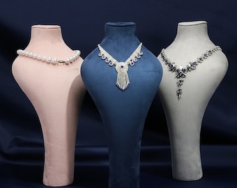 May include: Three velvet bust forms in pink, blue and grey, displaying necklaces with blue and white stones.