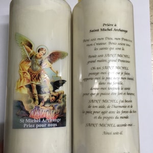 Peut inclure: Deux bougies de prière blanches avec des dessus jaunes. Les bougies présentent une image de Saint Michel Archange terrassant Satan. Le texte sur les bougies indique "Prière à Saint Michel Archange" et "St Michel Archange Priez pour nous".
