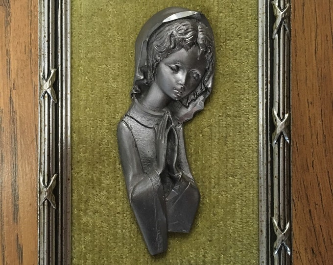 Painting in pewter and green velvet of a child who prays for communion or baptism.