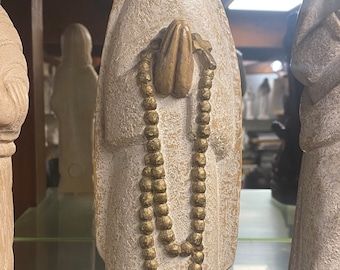 Statue of the Virgin Mary in stone holding a rosary