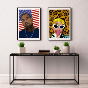 May include: Two framed art prints featuring pop art portraits. One depicts a person with a blue shirt and a gold chain against an American flag background. The other shows a person with sunglasses and a leopard print background.
