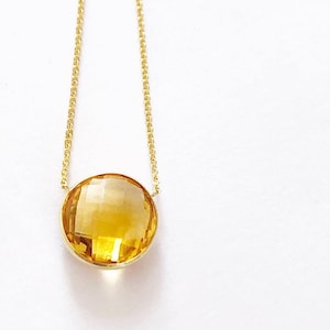 May include: A gold chain necklace with a large, round, faceted, yellow citrine gemstone pendant.