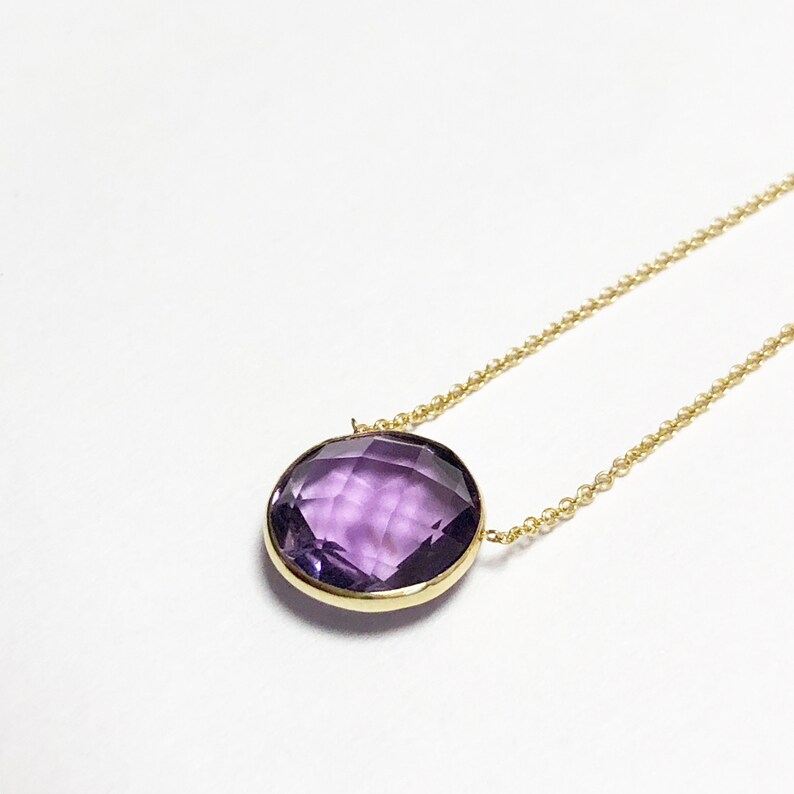 May include: A gold chain necklace with a large, round, faceted amethyst pendant.