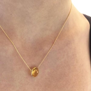 May include: A gold chain necklace with a single, round, yellow gemstone pendant.
