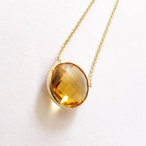 May include: A gold chain necklace with a large, round, faceted, yellow citrine gemstone pendant.
