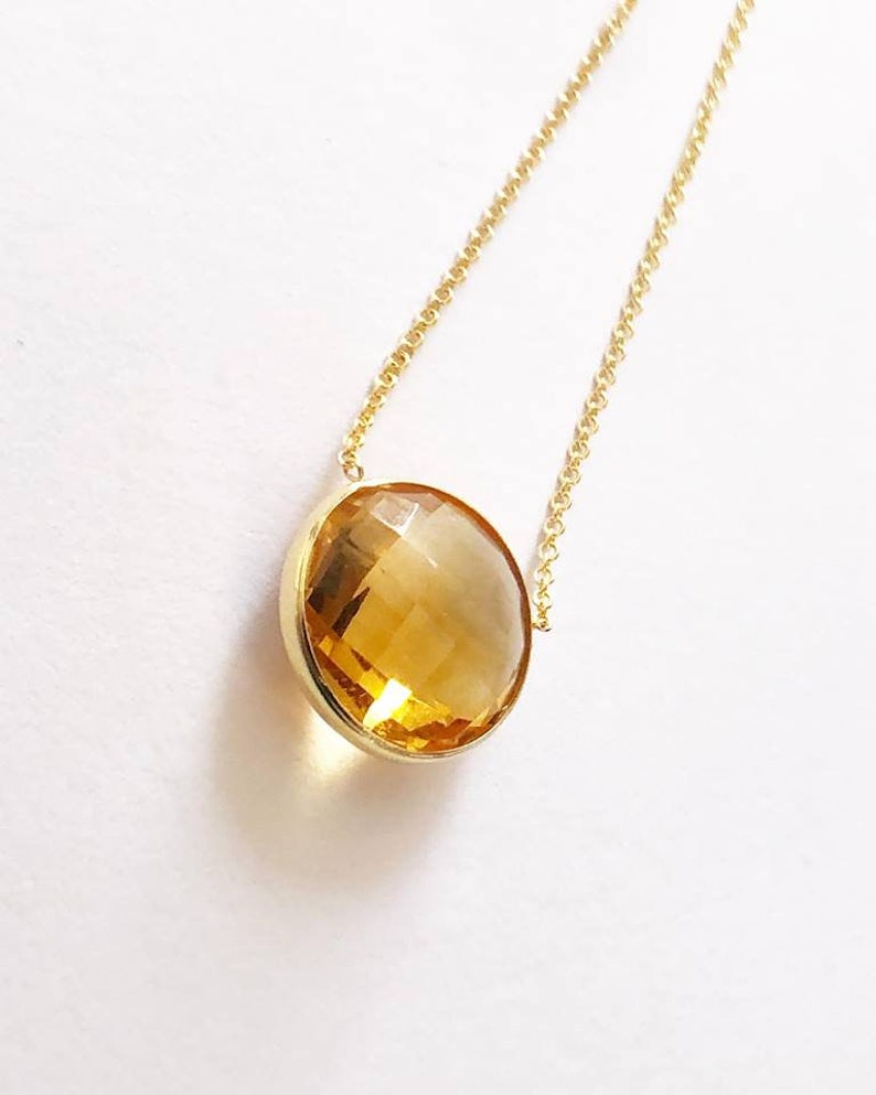 May include: A gold chain necklace with a large, round, faceted, yellow citrine gemstone pendant.