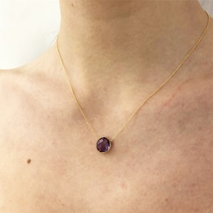 May include: A gold chain necklace with a large, round, faceted amethyst pendant.