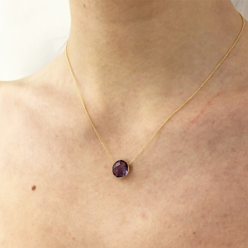 May include: A gold chain necklace with a large, round, faceted amethyst pendant.