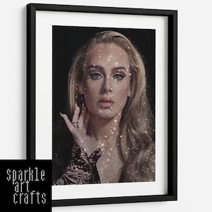 May include: A framed print of a woman with blonde hair and a glittery background. The woman is looking directly at the viewer. The background is a dark, starry night.