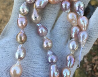 May include: A strand of pearlescent pink and white baroque pearls, strung on a white thread. The pearls are teardrop shaped and have a natural, irregular form.