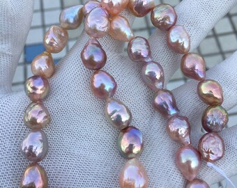 May include: A strand of iridescent pink and peach freshwater pearls. The pearls are baroque shaped and have a natural luster.