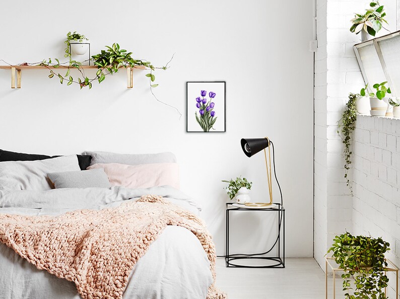 May include: A framed watercolor painting of a bouquet of purple tulips on a white background. The painting is hanging on a white wall in a bedroom setting.