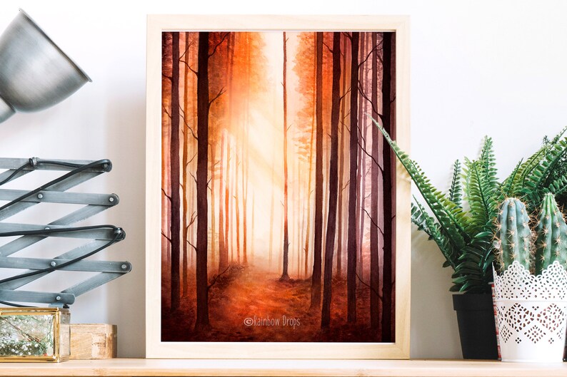 May include: A watercolour painting of a forest path with tall trees on either side. The trees are painted in shades of orange, red, and brown, and the path is illuminated by a bright light in the distance. The painting is framed in a simple wooden frame.