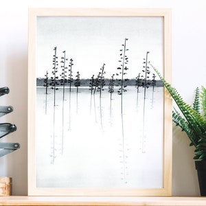 Pu&ograve; includere: Un disegno a inchiostro nero e bianco incorniciato di una scena di bosco con alberi riflessi in uno specchio d'acqua. Il disegno &egrave; in una cornice di legno chiaro ed &egrave; appeso a una parete bianca.