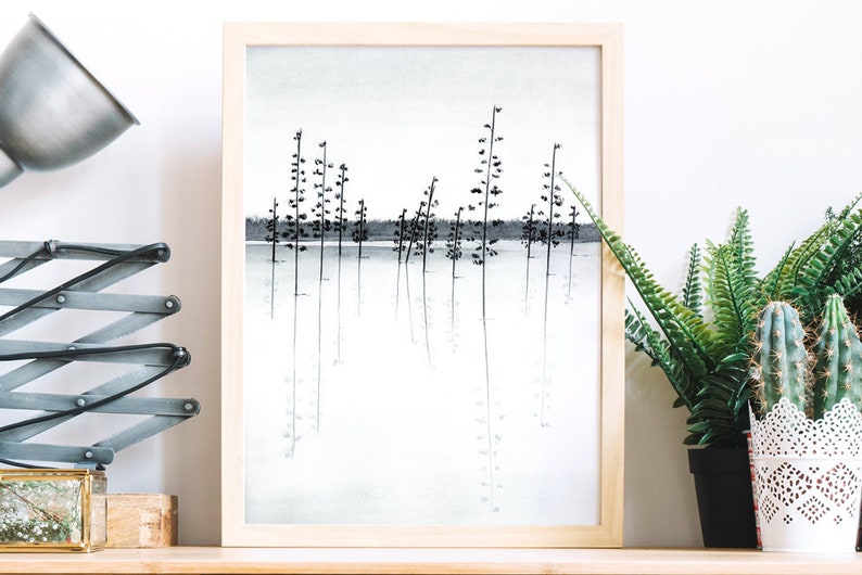 Pu&ograve; includere: Un disegno a inchiostro nero e bianco incorniciato di una scena di bosco con alberi riflessi in uno specchio d'acqua. Il disegno &egrave; in una cornice di legno chiaro ed &egrave; appeso a una parete bianca.