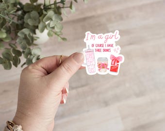 May include: Pink and white sticker with the text "I'm a girl, of course I have three drinks" and illustrations of three pink drinks.