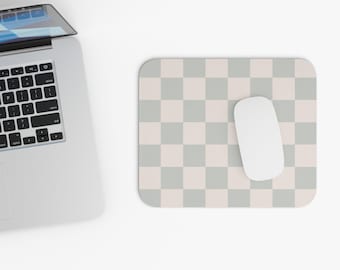 Peut inclure: Une souris d'ordinateur blanche sur un tapis de souris à carreaux gris et blancs. Le tapis de souris est sur une surface blanche. Un ordinateur portable est en arrière-plan.