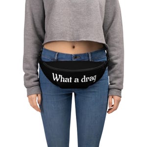 May include: A black fanny pack with a white text overlay that reads "What a drag".