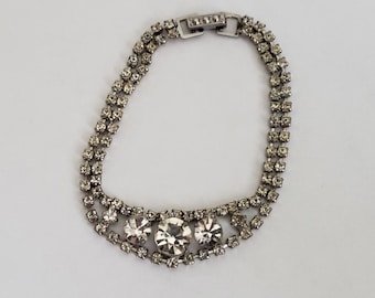 May include: A silver bracelet with a double row of clear rhinestones and three larger rhinestones in the center.
