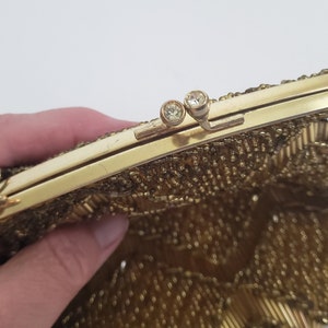 Pu&ograve; includere: Una borsa da sera in perline dorate con una chiusura in metallo dorato e due strass trasparenti. La borsa &egrave; realizzata con una fine rete di perline dorate.